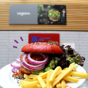 Veganer Burger mit Pommes und Salat vor dem veganen Schalter der Mensa am Park