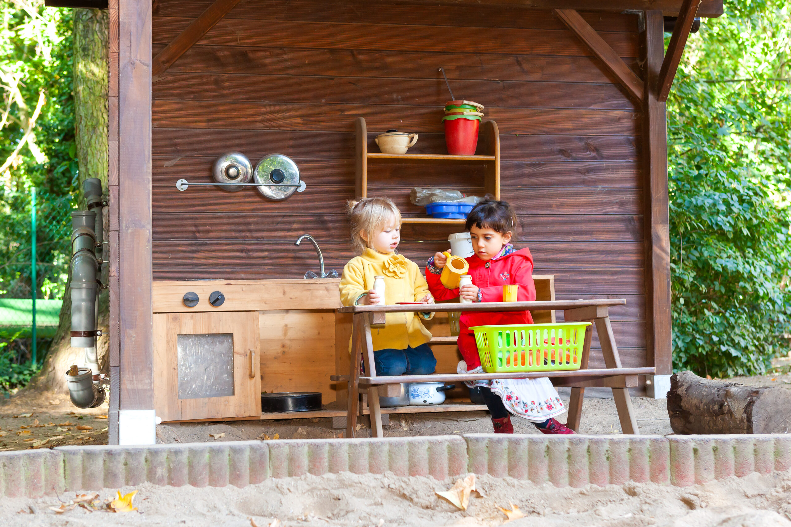 Zwei Kinder spielen in einer Matschküche.