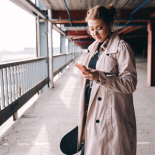 Eine junge Frau mit einem Smartphone in der Hand.