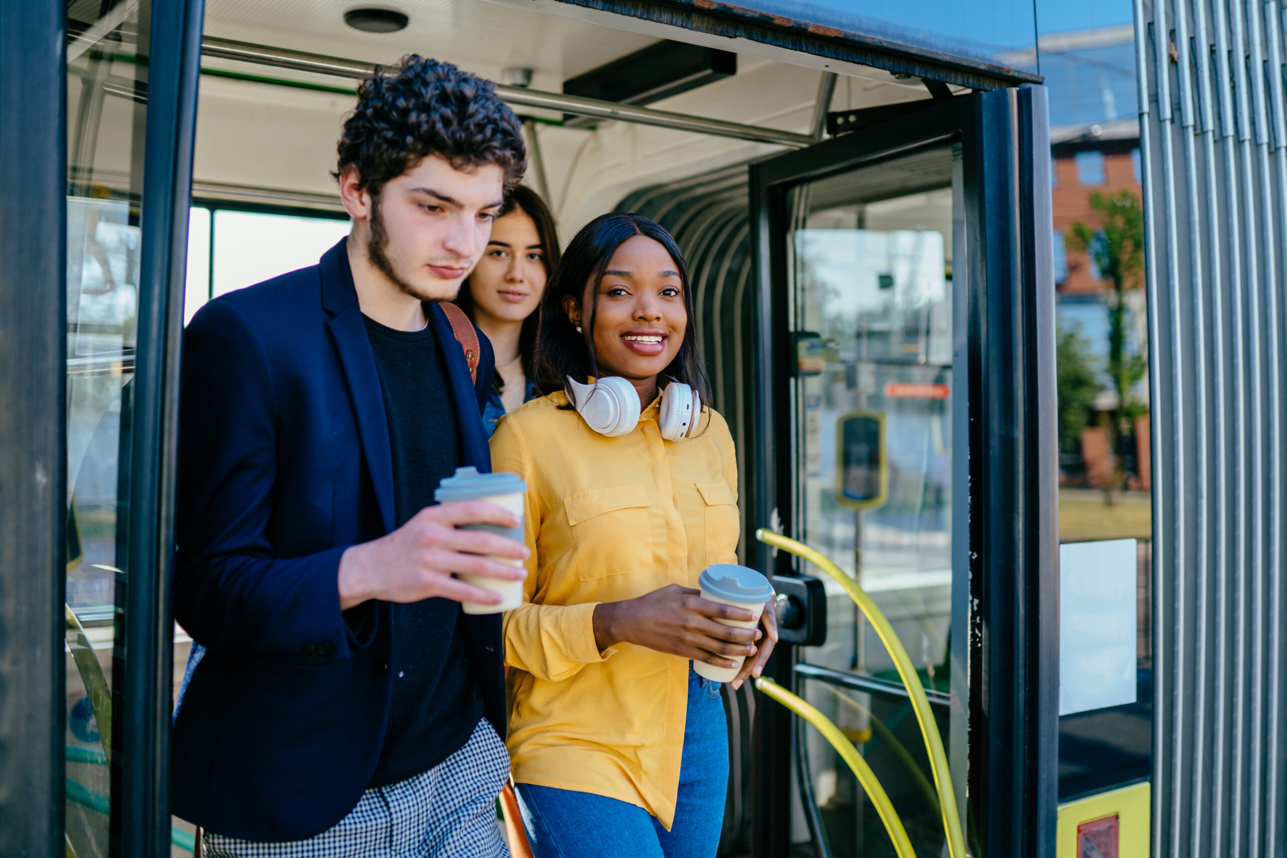 Drei junge Menschen steigen aus einem Bus aus.