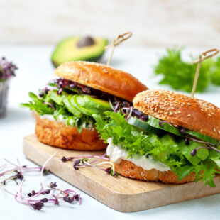 green burger with avocado, cucumber, cream cheese and micro greens on a cutting board