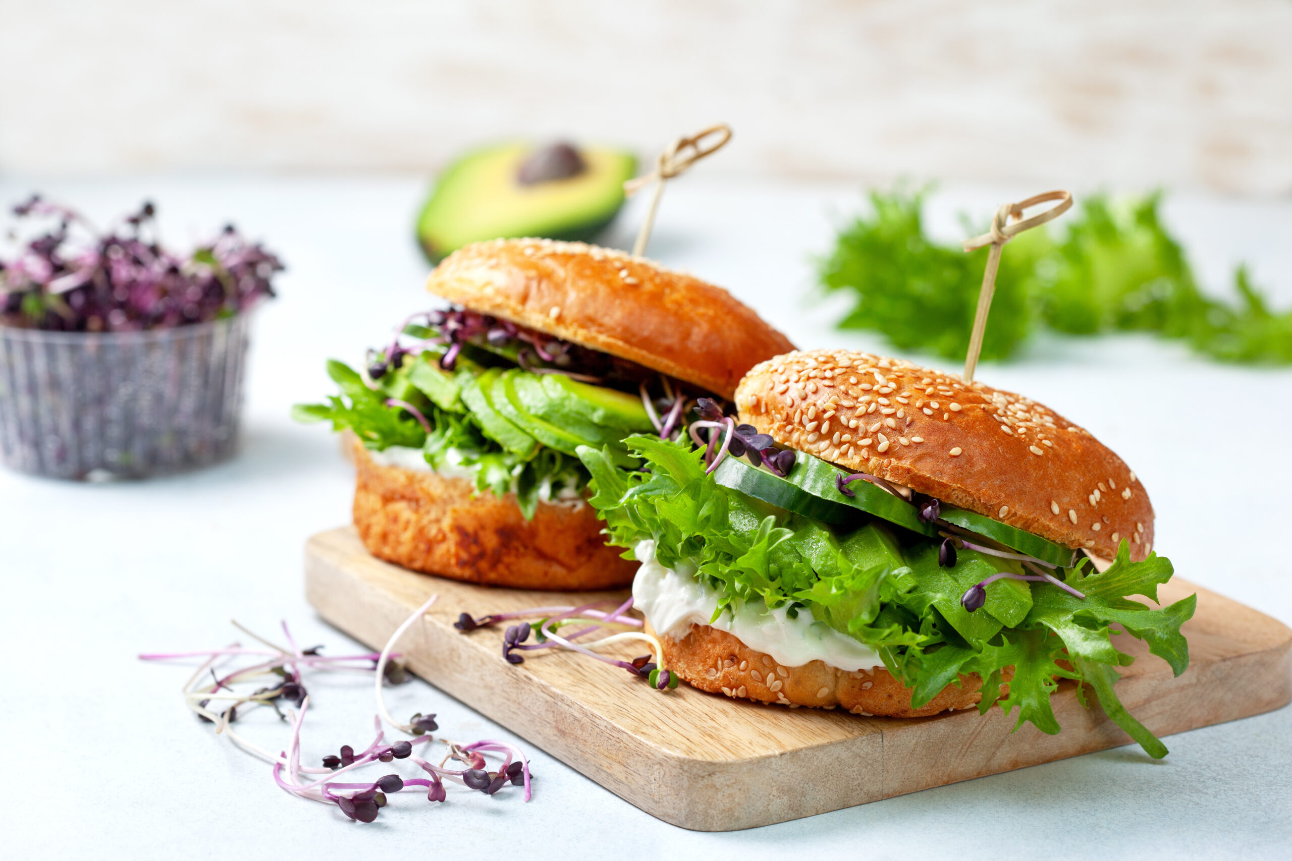 green burger with avocado, cucumber, cream cheese and micro greens on a cutting board