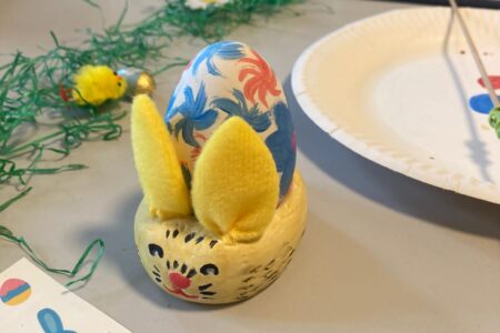 A painted Easter egg in a bunny-shaped egg cup.